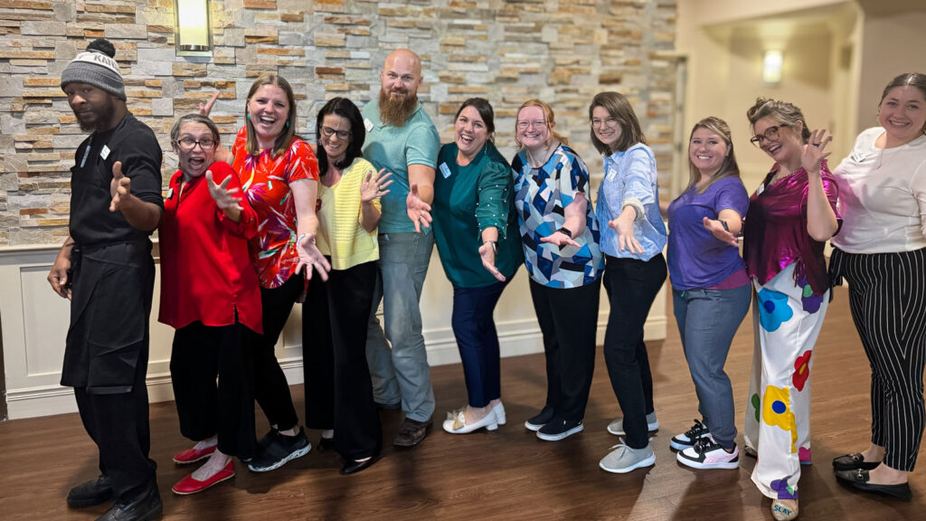 A lively group of Parkway team members poses enthusiastically in colorful attire, exuding camaraderie and team spirit in a fun and engaging community setting.