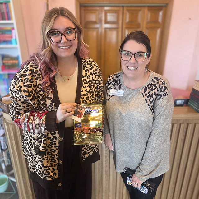 A team member at The Parkway Senior Living smiles with a local business owner, gifting chocolates.