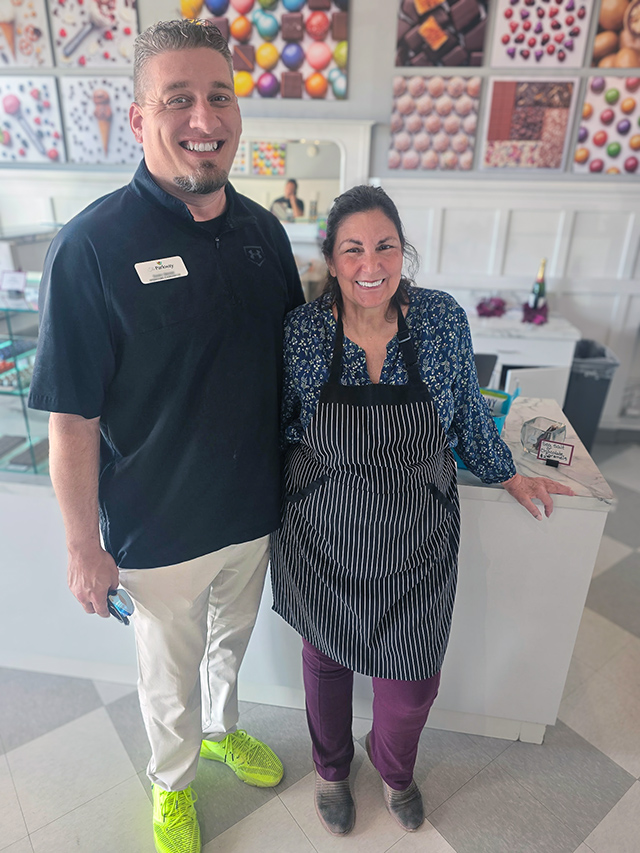 A man on the Parkway Senior Living team smiles alongside the owner of a local confectionary.