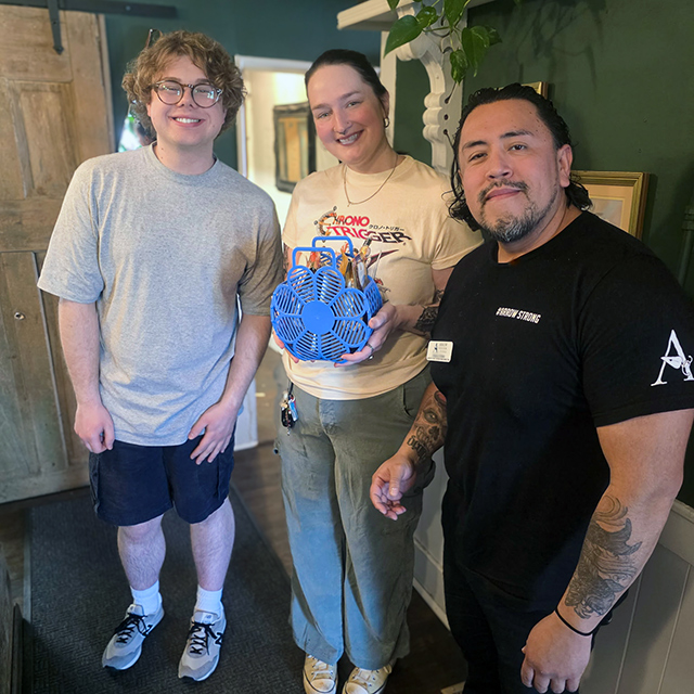 A team member at The Parkway Senior Living gifts a basket of goodies to a man and woman at a local business.